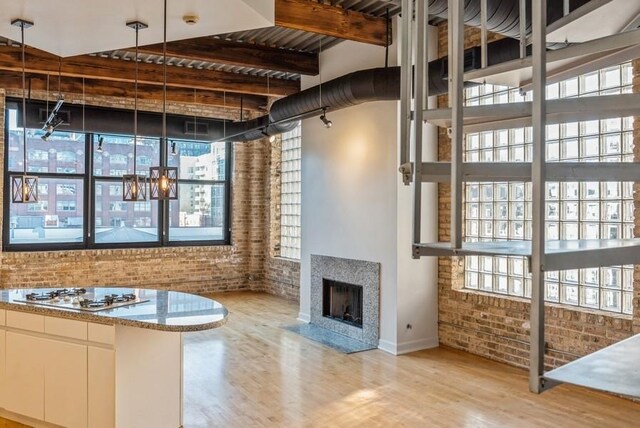 interior space with light wood-type flooring, beamed ceiling, and brick wall