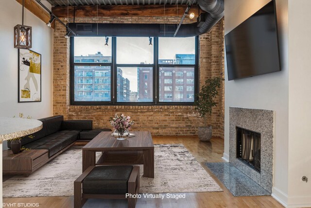 living room featuring brick wall, beamed ceiling, and wood-type flooring