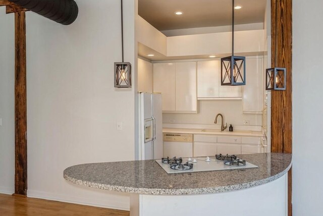 kitchen featuring sink, hardwood / wood-style flooring, light stone counters, white appliances, and white cabinetry