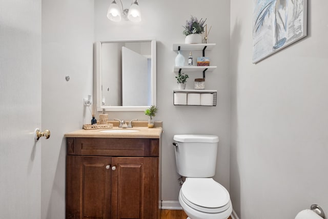 bathroom featuring a notable chandelier, vanity, toilet, and baseboards