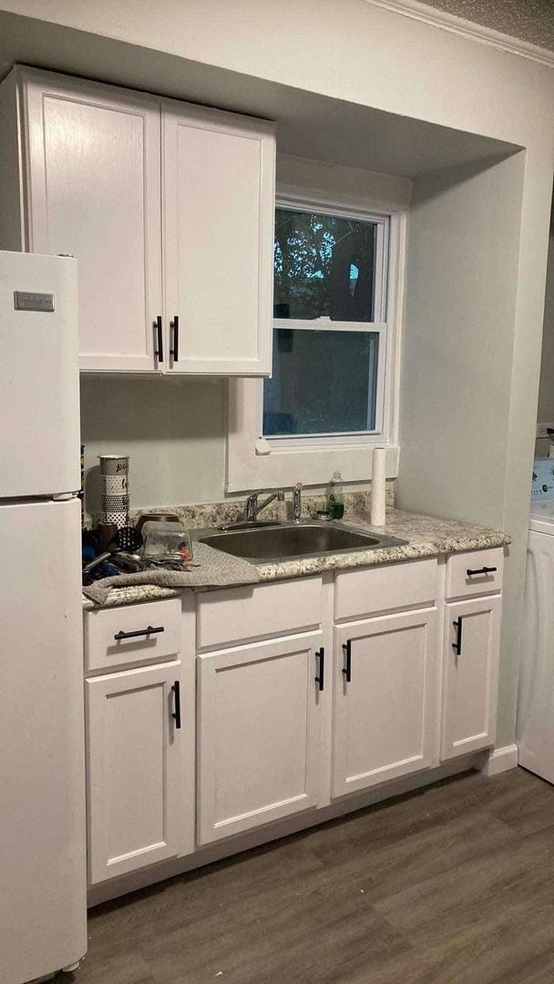 kitchen featuring dark hardwood / wood-style floors, white refrigerator, ornamental molding, white cabinets, and sink