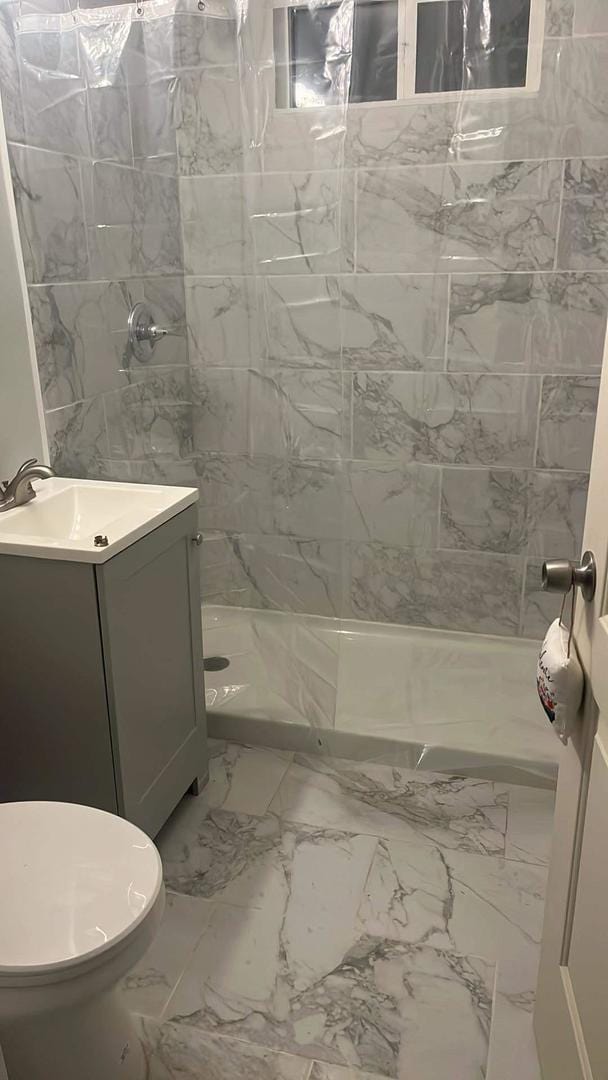 bathroom with tiled shower, toilet, tile patterned floors, and vanity