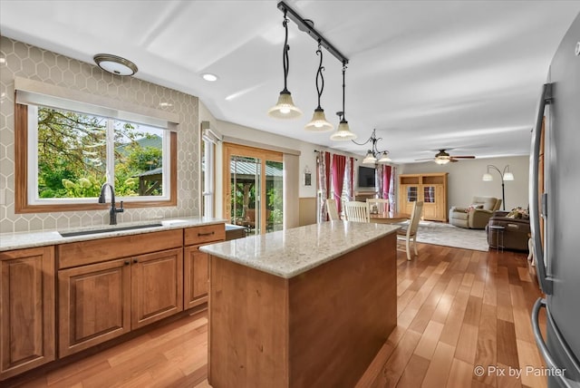 kitchen featuring light hardwood / wood-style flooring, light stone counters, sink, and hanging light fixtures