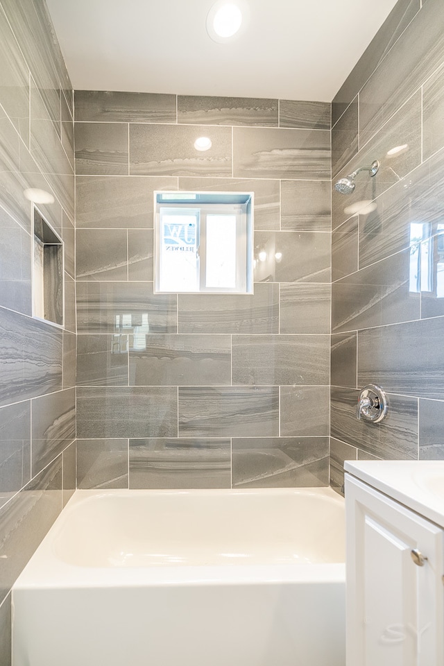 bathroom featuring tiled shower / bath combo and vanity