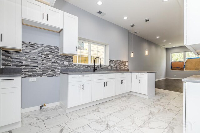 kitchen with light hardwood / wood-style flooring, tasteful backsplash, white cabinetry, sink, and decorative light fixtures