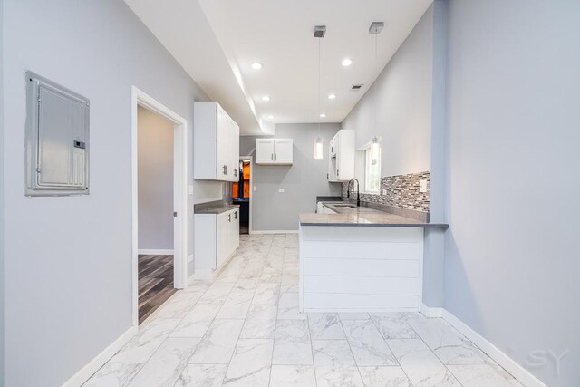 kitchen featuring light hardwood / wood-style flooring, white cabinetry, electric panel, sink, and kitchen peninsula