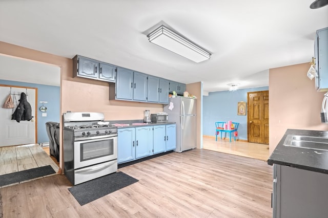 kitchen featuring blue cabinets, light hardwood / wood-style flooring, and white appliances