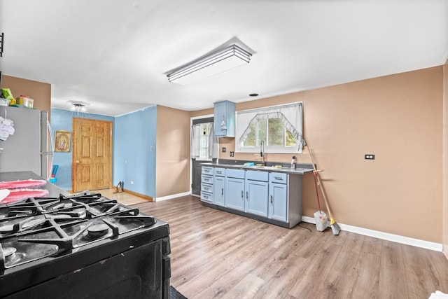 kitchen with light hardwood / wood-style floors, sink, blue cabinetry, stove, and stainless steel fridge