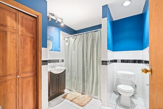 bathroom with tile walls, toilet, vanity, and tile patterned floors