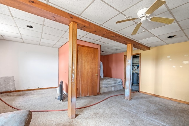 basement with a drop ceiling, carpet floors, and ceiling fan