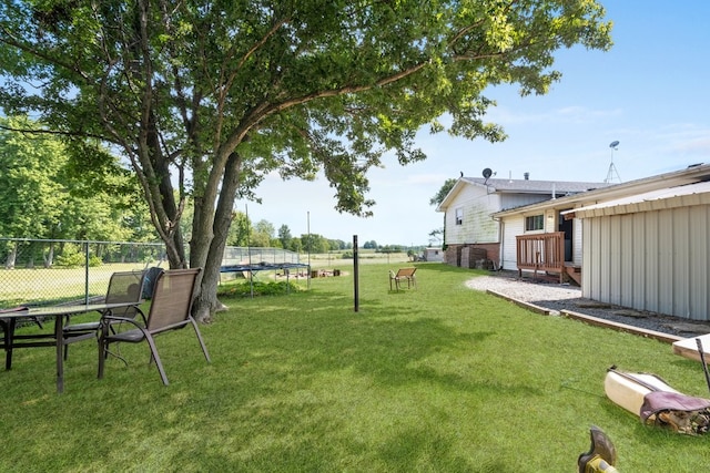 view of yard featuring a wooden deck and a trampoline