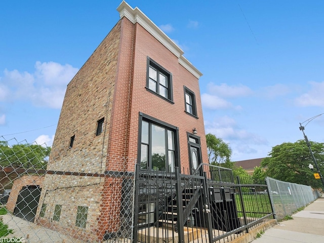 view of property exterior with stone siding, fence, and brick siding