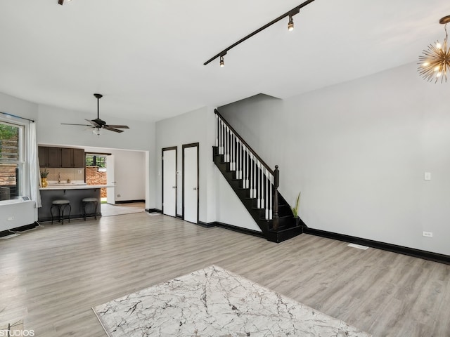 living room with track lighting, ceiling fan with notable chandelier, and light hardwood / wood-style flooring