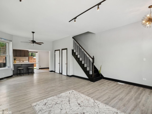 living area with light wood finished floors, stairs, baseboards, and a ceiling fan