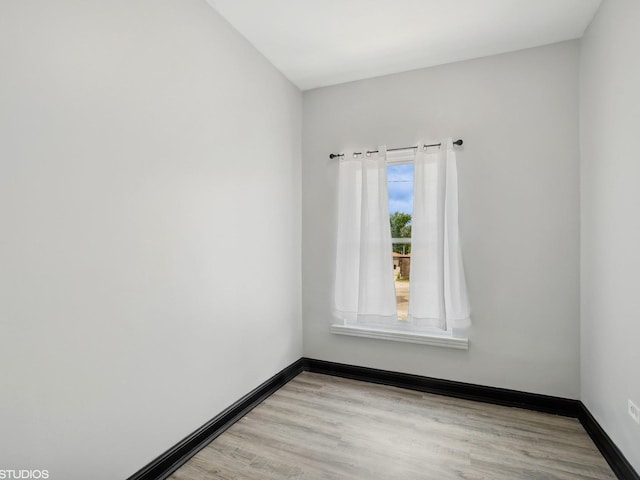 spare room featuring baseboards and light wood finished floors