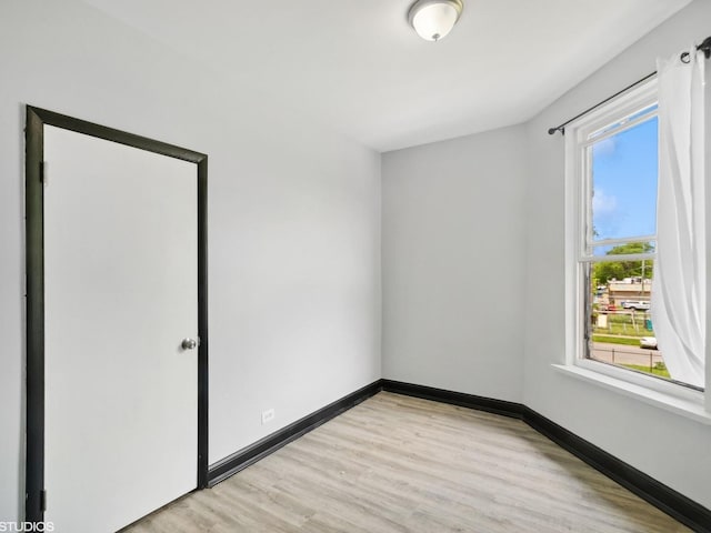 spare room featuring baseboards and light wood-type flooring
