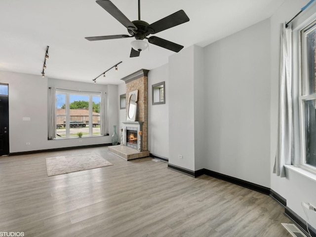 unfurnished living room featuring visible vents, baseboards, a fireplace, ceiling fan, and wood finished floors