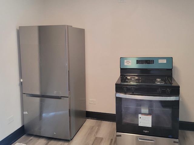 kitchen with baseboards, wood finished floors, and appliances with stainless steel finishes
