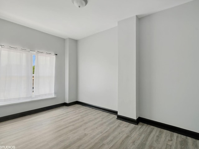 spare room featuring baseboards and wood finished floors