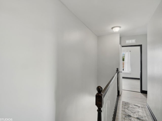 hall featuring baseboards, an upstairs landing, visible vents, and light wood-type flooring