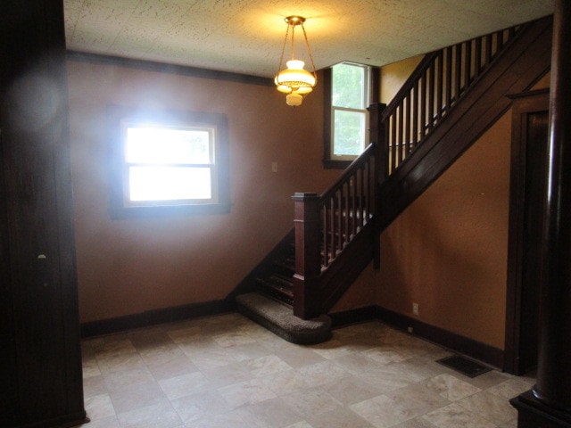 staircase featuring tile patterned flooring, plenty of natural light, and a textured ceiling