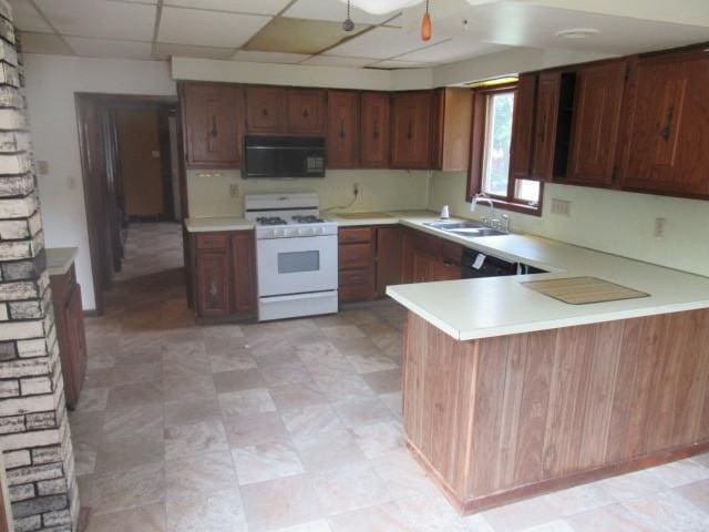 kitchen with white gas range, sink, a paneled ceiling, and kitchen peninsula