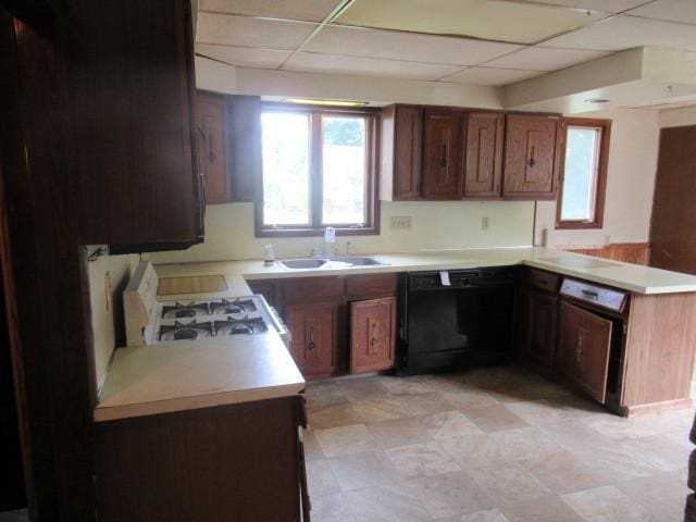 kitchen with white gas range, kitchen peninsula, a paneled ceiling, and dishwasher