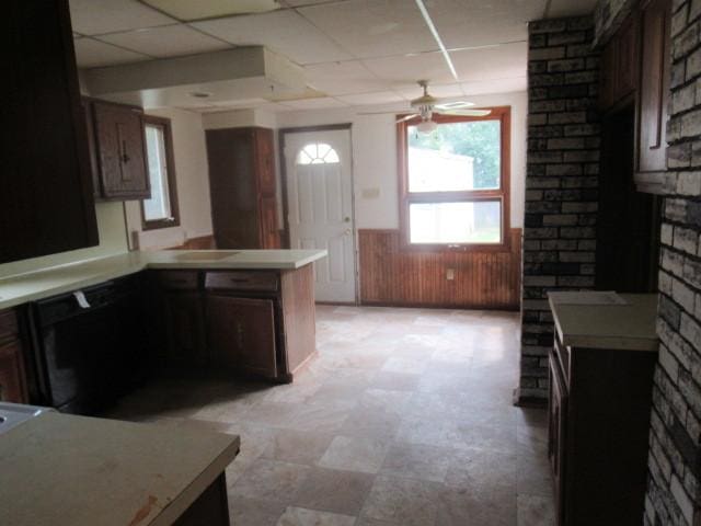 kitchen featuring ceiling fan, a drop ceiling, kitchen peninsula, and wooden walls