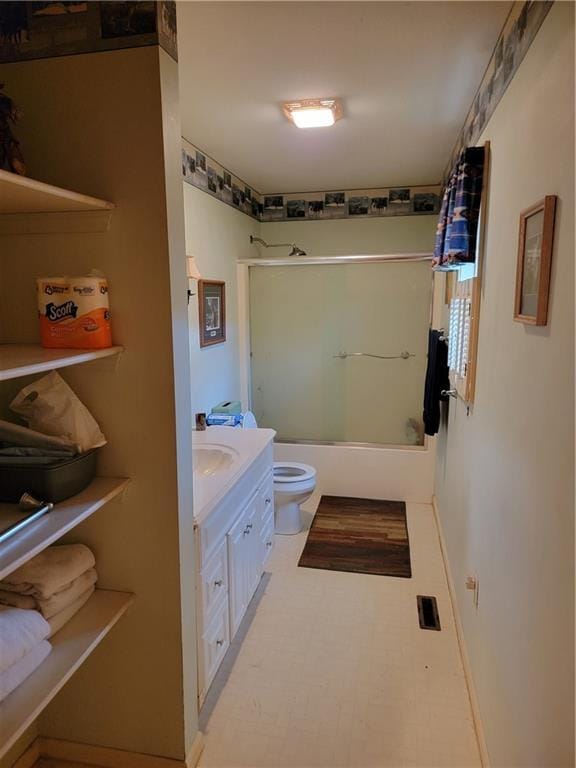 full bathroom featuring vanity, toilet, and bath / shower combo with glass door