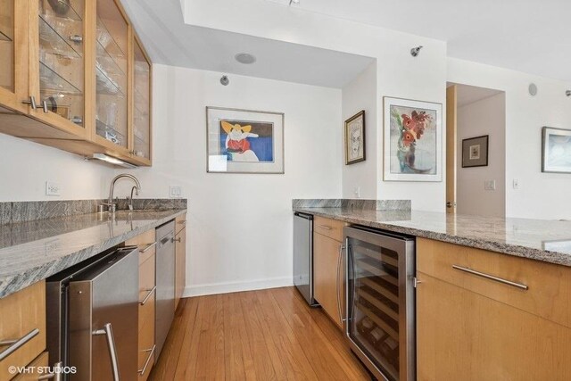 kitchen featuring sink, wine cooler, light stone countertops, light hardwood / wood-style floors, and dishwasher