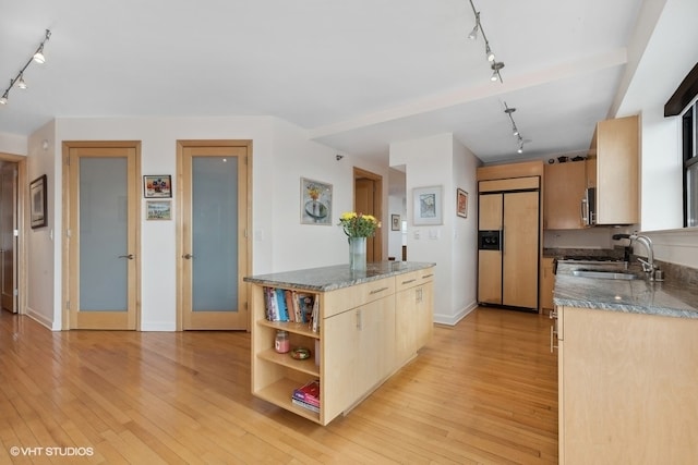 kitchen featuring paneled built in refrigerator, track lighting, light wood-type flooring, and dark stone counters