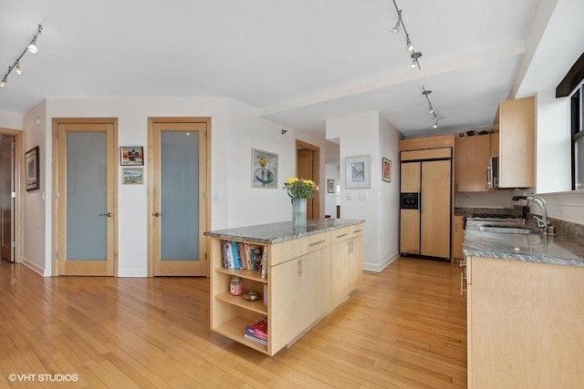 kitchen featuring rail lighting, sink, light wood-type flooring, paneled built in refrigerator, and dark stone counters