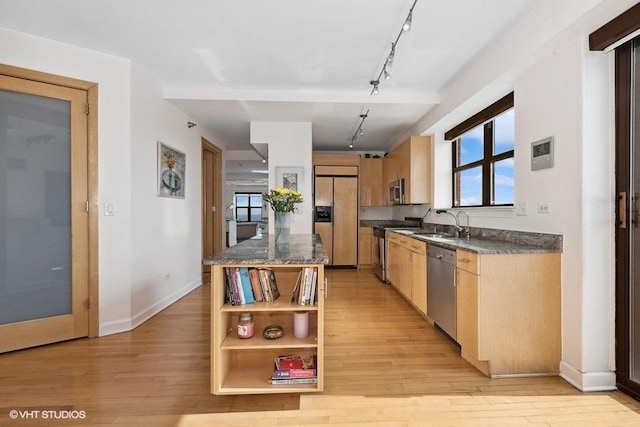 kitchen featuring sink, track lighting, appliances with stainless steel finishes, a kitchen island, and light hardwood / wood-style floors