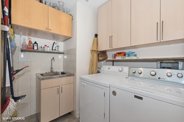 laundry area with cabinets, tile walls, light tile patterned floors, washer and clothes dryer, and sink