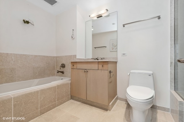 bathroom with tile patterned flooring, a relaxing tiled tub, toilet, and vanity