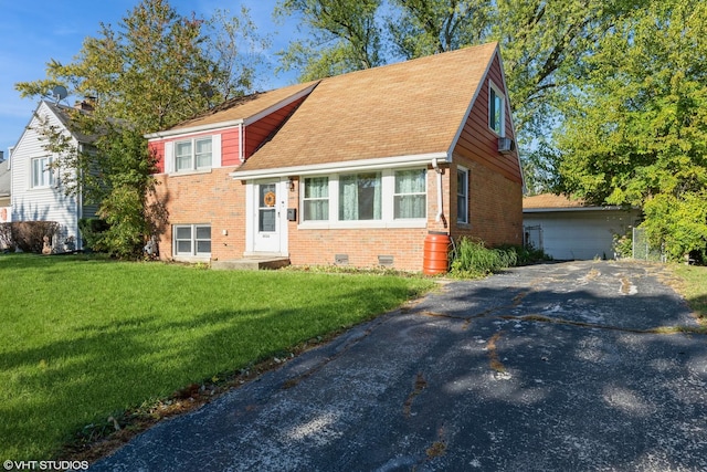tri-level home with roof with shingles, a front yard, brick siding, and an outbuilding