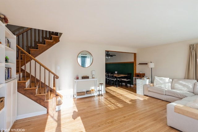 living room featuring a ceiling fan, stairway, and wood finished floors