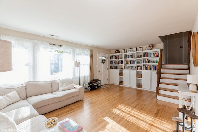 living area featuring stairway, wood finished floors, and visible vents