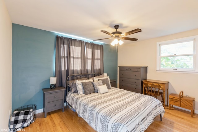 bedroom featuring a ceiling fan, light wood-style flooring, and baseboards