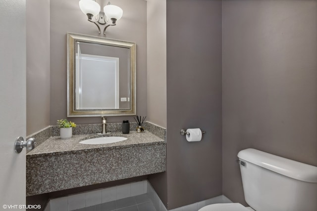 bathroom featuring an inviting chandelier, tile patterned floors, sink, and toilet