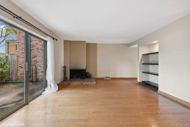 unfurnished living room featuring a fireplace and light hardwood / wood-style floors