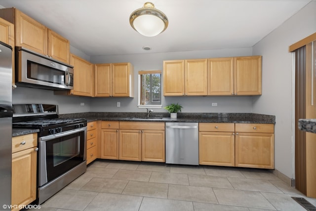 kitchen with light brown cabinets, light tile patterned flooring, stainless steel appliances, and sink