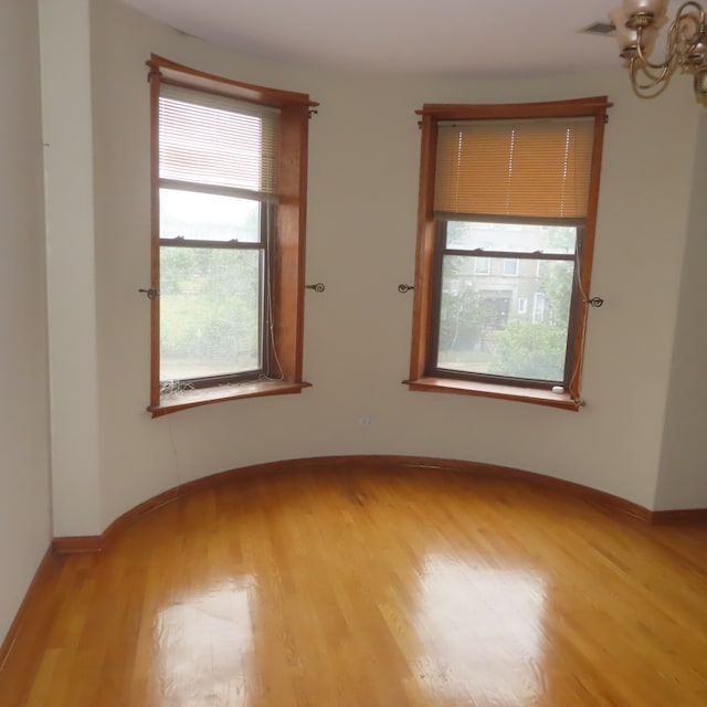 unfurnished room with a chandelier and light hardwood / wood-style floors