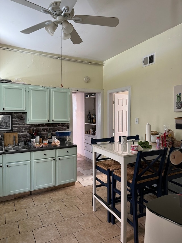 kitchen featuring green cabinets, ceiling fan, light tile patterned floors, and sink