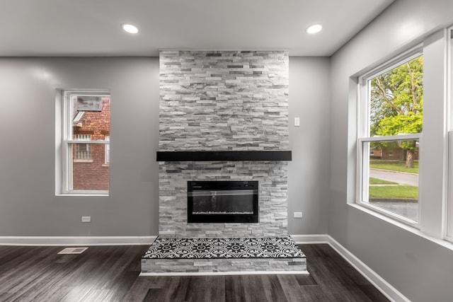 unfurnished living room featuring dark hardwood / wood-style floors and a stone fireplace