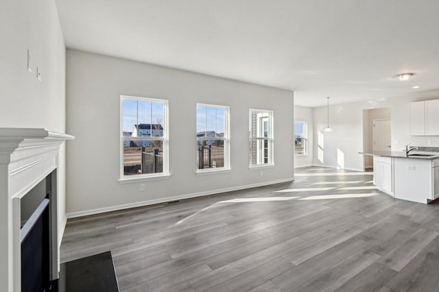 unfurnished living room featuring sink and light hardwood / wood-style floors