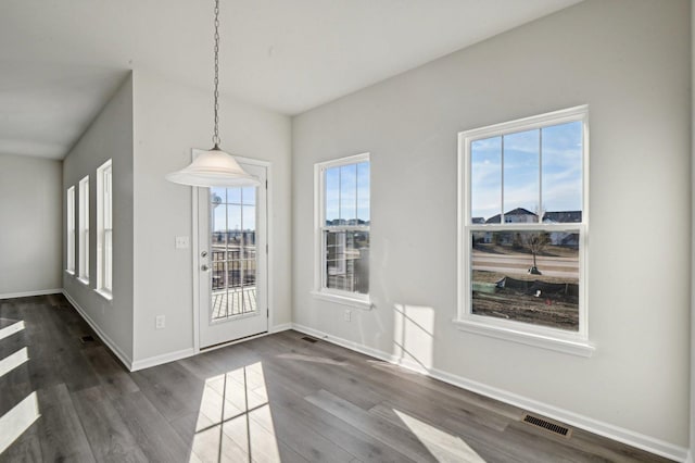 unfurnished dining area with dark wood-type flooring