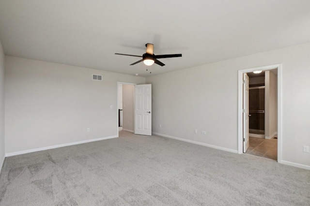 unfurnished bedroom with connected bathroom, light carpet, and ceiling fan