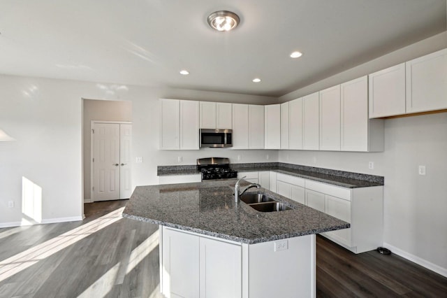 kitchen featuring dark wood-type flooring, sink, white cabinetry, an island with sink, and stainless steel appliances