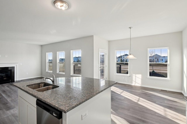 kitchen with decorative light fixtures, sink, white cabinets, dark stone counters, and stainless steel dishwasher